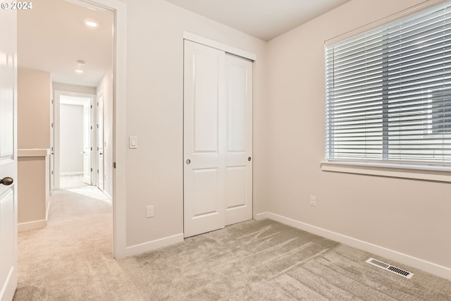 unfurnished bedroom featuring light carpet and a closet