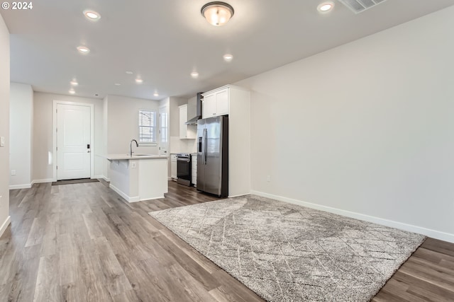 kitchen featuring white cabinets, hardwood / wood-style floors, stainless steel appliances, and an island with sink