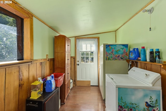 laundry room featuring light wood finished floors, crown molding, a wainscoted wall, cabinet space, and washer / clothes dryer