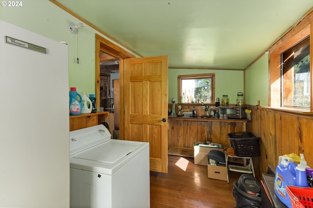 washroom with crown molding, dark wood-type flooring, wood walls, and washer / clothes dryer