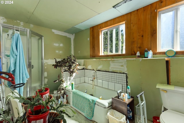 bathroom featuring shower with separate bathtub, toilet, and wooden walls