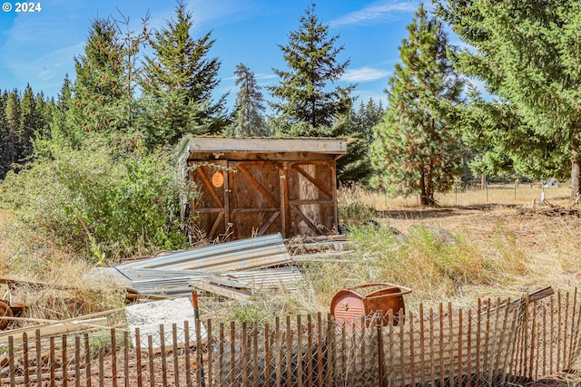 view of yard featuring a storage shed, an outbuilding, and fence