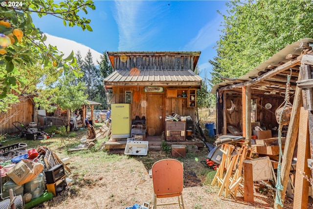 rear view of property featuring an outbuilding, metal roof, and fence