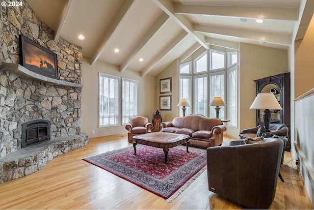 living room featuring light wood-style flooring, beamed ceiling, a stone fireplace, and high vaulted ceiling