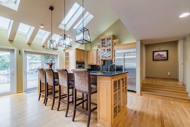 kitchen with a skylight, pendant lighting, appliances with stainless steel finishes, glass insert cabinets, and a kitchen island