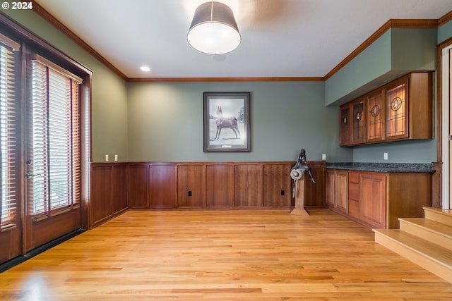 bar featuring light wood-style flooring, ornamental molding, and wainscoting