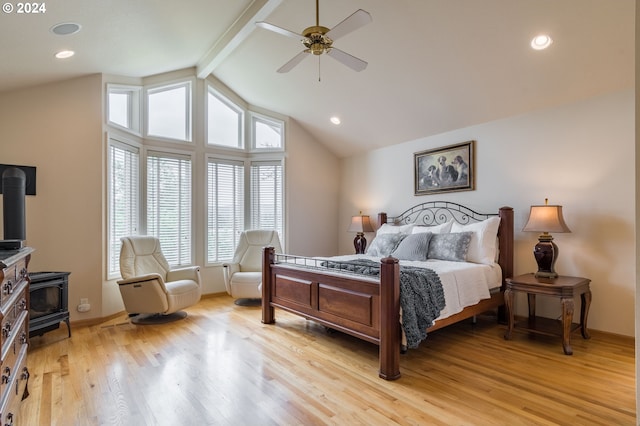 bedroom with light wood finished floors, recessed lighting, lofted ceiling with beams, a ceiling fan, and a wood stove