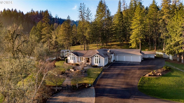 view of front of house with driveway and a view of trees