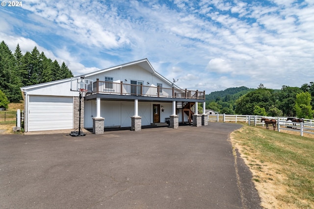 view of front facade with a garage, driveway, a wooden deck, and fence