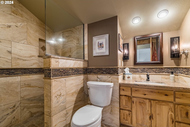 full bath featuring tile walls, vanity, toilet, and a walk in shower