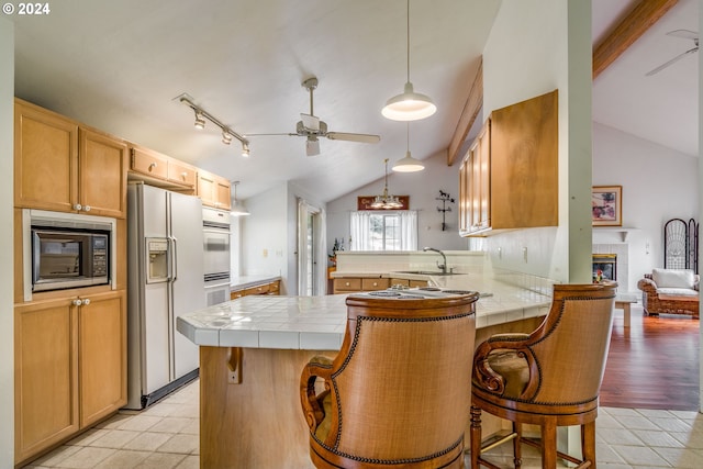 kitchen featuring a peninsula, white appliances, tile countertops, and a breakfast bar area