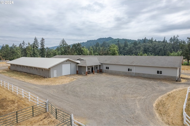 view of front of house featuring driveway, a forest view, and an attached garage