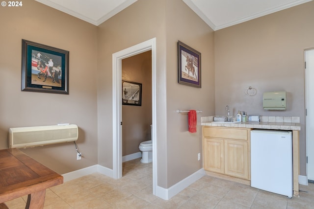 bathroom featuring toilet, baseboards, crown molding, and tile patterned floors