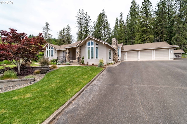 view of front facade with a garage, a front yard, a chimney, and aphalt driveway