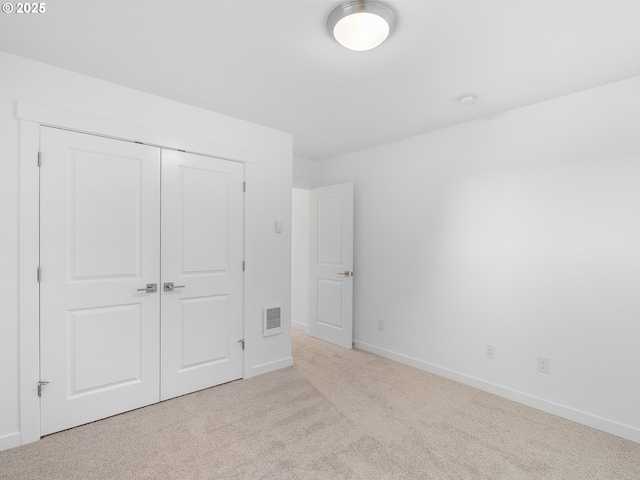 unfurnished bedroom with light colored carpet and a closet