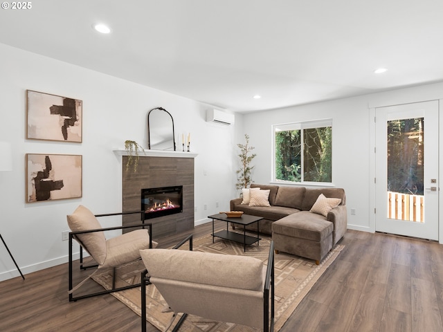 living room with a tiled fireplace, wood-type flooring, and a wall mounted AC