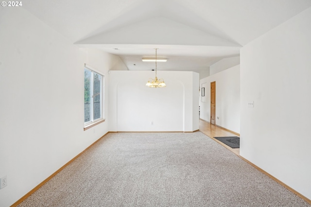 carpeted empty room featuring vaulted ceiling and an inviting chandelier