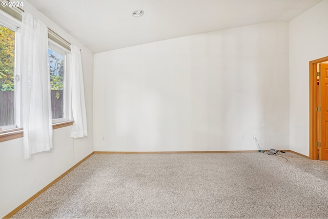 carpeted empty room featuring vaulted ceiling