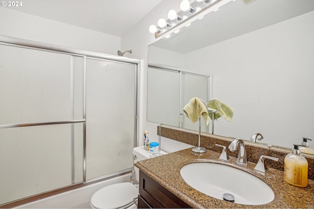 full bathroom featuring combined bath / shower with glass door, vanity, and toilet