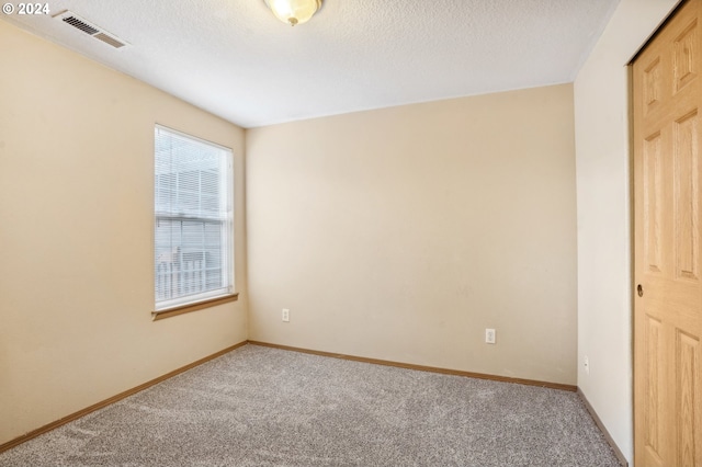 carpeted empty room with a textured ceiling