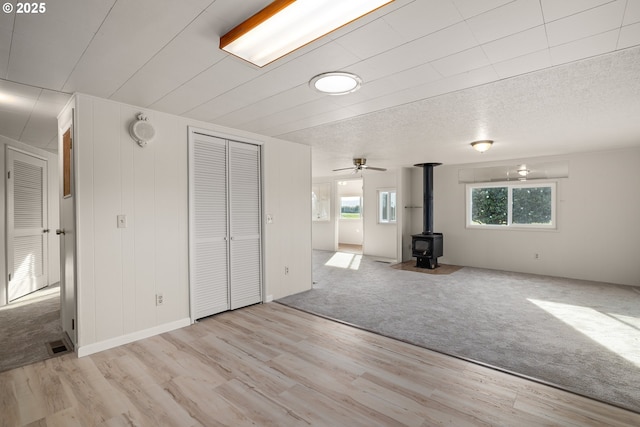 unfurnished living room featuring a wood stove and light colored carpet