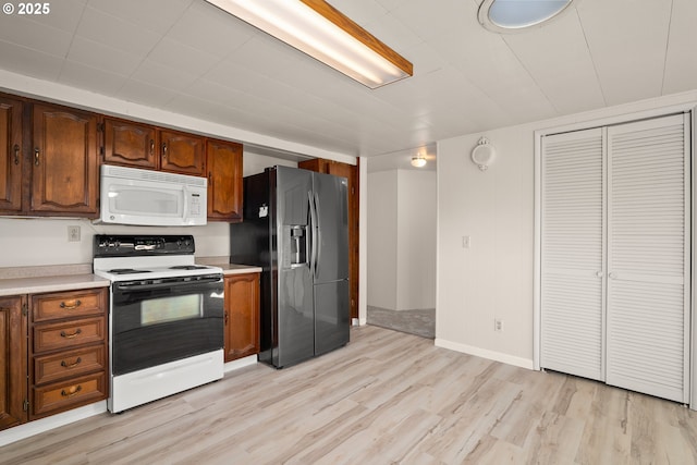 kitchen with stainless steel fridge with ice dispenser, electric range, and light hardwood / wood-style floors