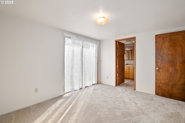 unfurnished bedroom featuring light carpet and connected bathroom