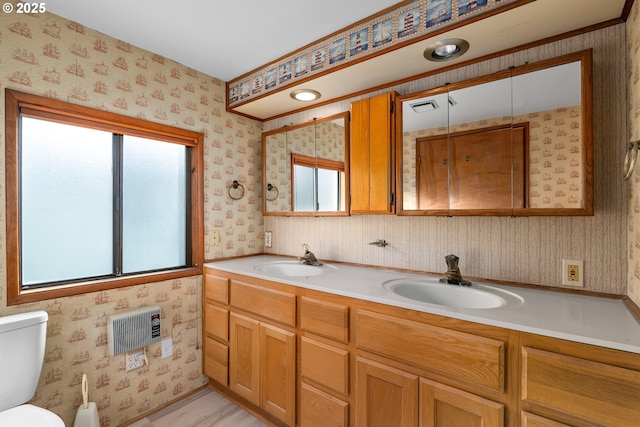 bathroom featuring vanity, heating unit, and toilet