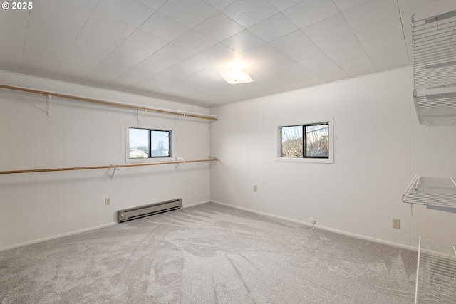 basement featuring a baseboard heating unit, a healthy amount of sunlight, and carpet flooring