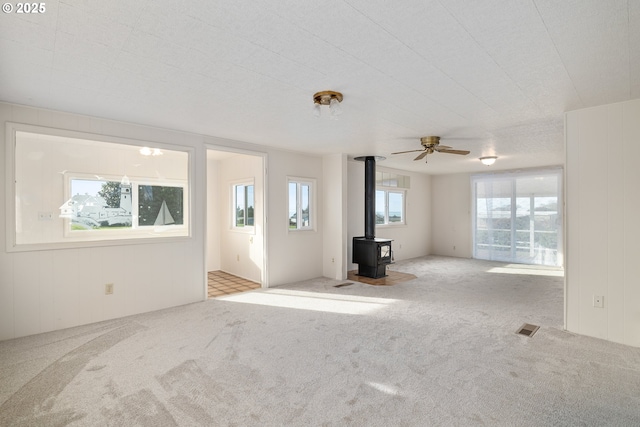 unfurnished living room featuring light carpet and a wood stove