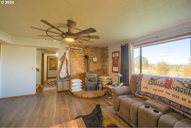 living room with a wood stove, ceiling fan, hardwood / wood-style floors, and a textured ceiling