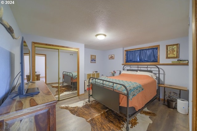 bedroom featuring wood-type flooring, a textured ceiling, and a closet