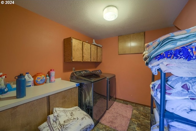 clothes washing area with cabinets, a textured ceiling, and washing machine and dryer