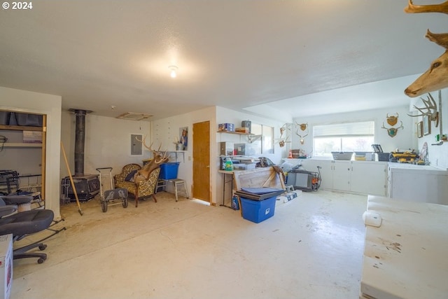 interior space featuring concrete flooring, electric panel, a wood stove, and blue cabinetry