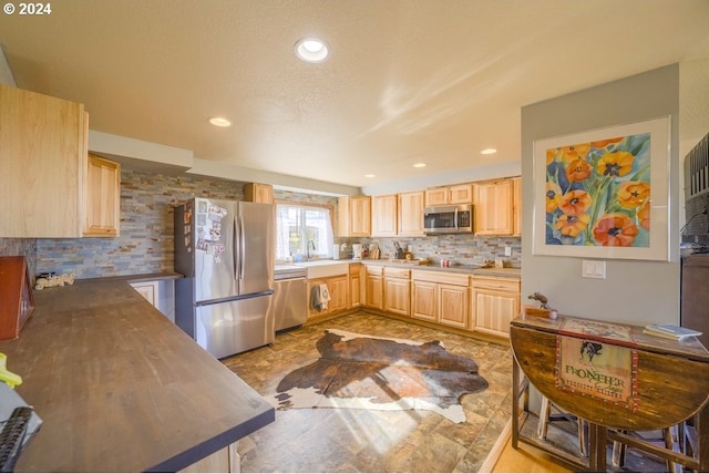 kitchen featuring a textured ceiling, sink, stainless steel appliances, and light brown cabinetry