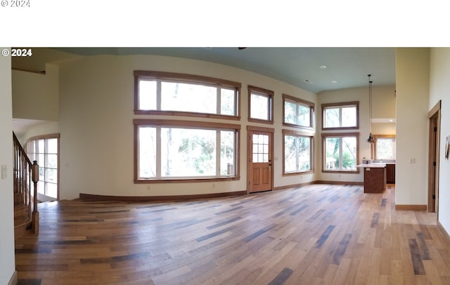 unfurnished living room with hardwood / wood-style floors and a towering ceiling