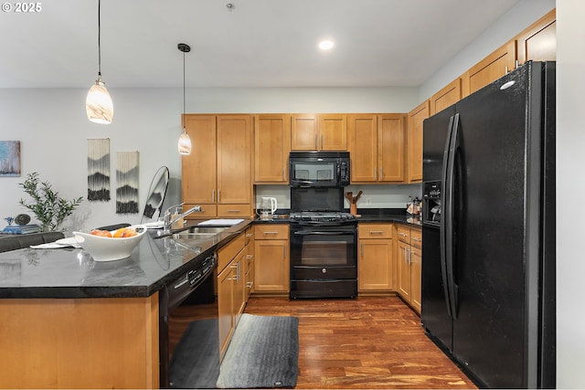 kitchen with black appliances, hanging light fixtures, sink, and dark wood-type flooring