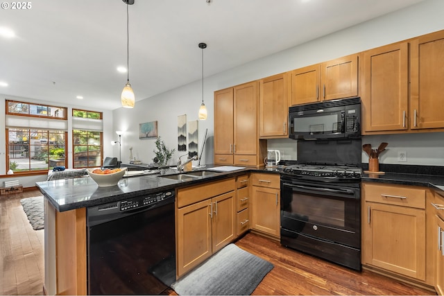 kitchen with black appliances, kitchen peninsula, pendant lighting, dark hardwood / wood-style floors, and sink