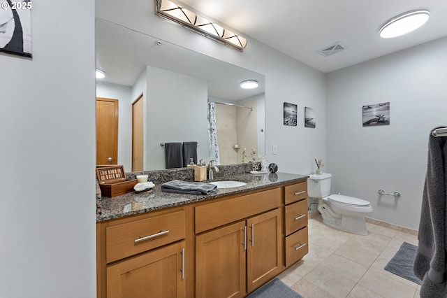 bathroom with toilet, vanity, tile patterned flooring, and walk in shower