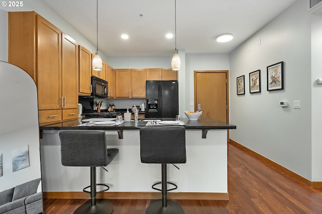 kitchen with a kitchen breakfast bar, pendant lighting, kitchen peninsula, black appliances, and dark wood-type flooring