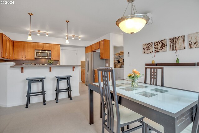 dining space featuring light colored carpet and rail lighting