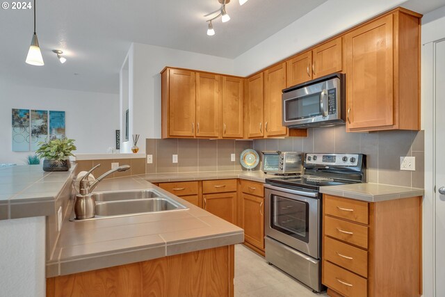 kitchen featuring hanging light fixtures, sink, appliances with stainless steel finishes, and kitchen peninsula