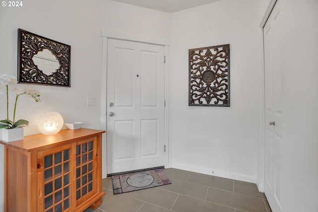 foyer featuring dark tile patterned flooring and baseboards