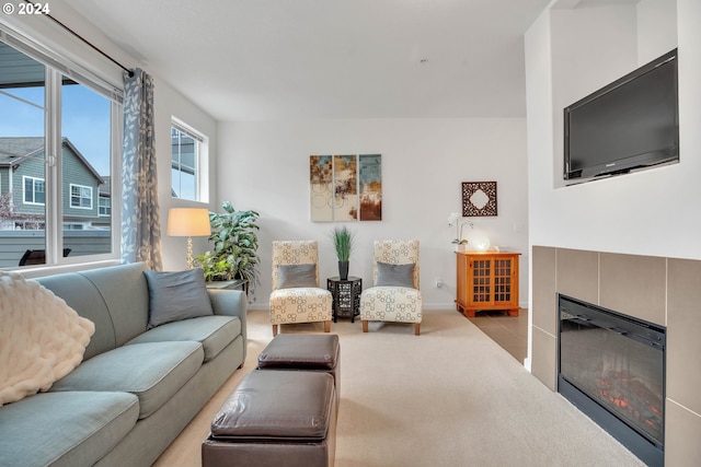 carpeted living room featuring a tiled fireplace and baseboards