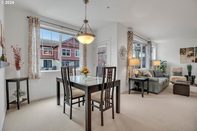 dining space featuring light colored carpet and baseboards