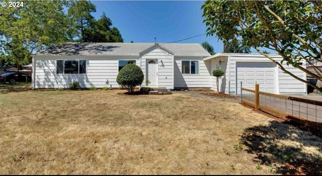 rear view of house featuring a lawn and a garage