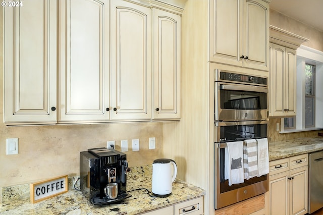 kitchen with light stone counters, stainless steel appliances, and cream cabinets