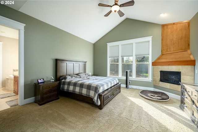 bedroom featuring a tiled fireplace, ceiling fan, vaulted ceiling, carpet floors, and ensuite bathroom