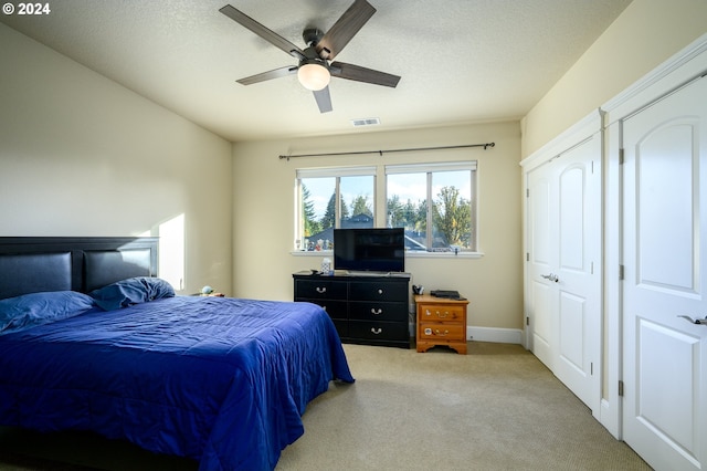 carpeted bedroom with a closet, ceiling fan, and a textured ceiling