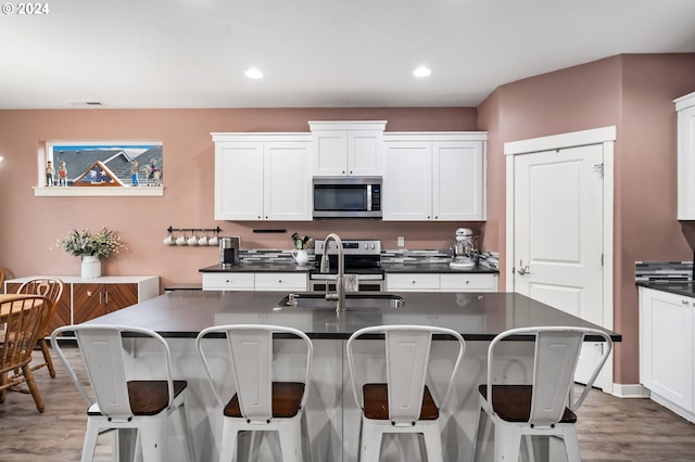 kitchen featuring white cabinetry, sink, dark hardwood / wood-style floors, an island with sink, and appliances with stainless steel finishes